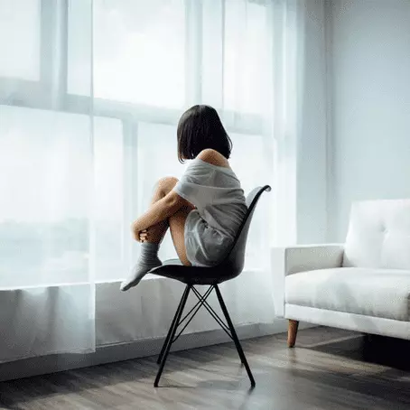 image of a girl sitting alone in front of the window