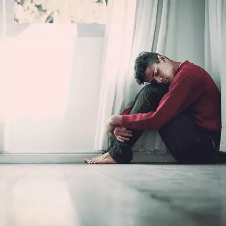 image of a man with depression sitting on the floor